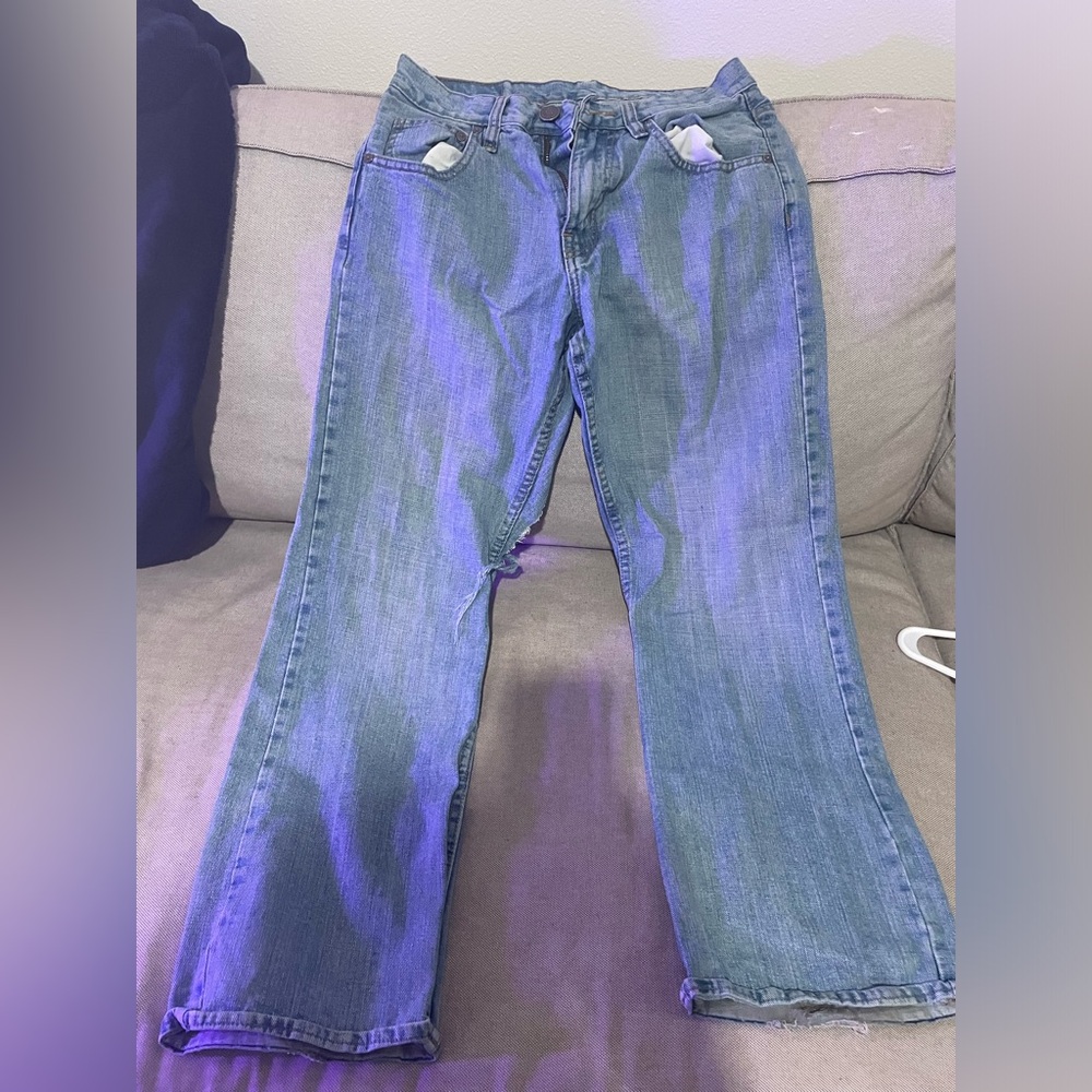 Blue boot cut jeans with a rip on the back of the leg.